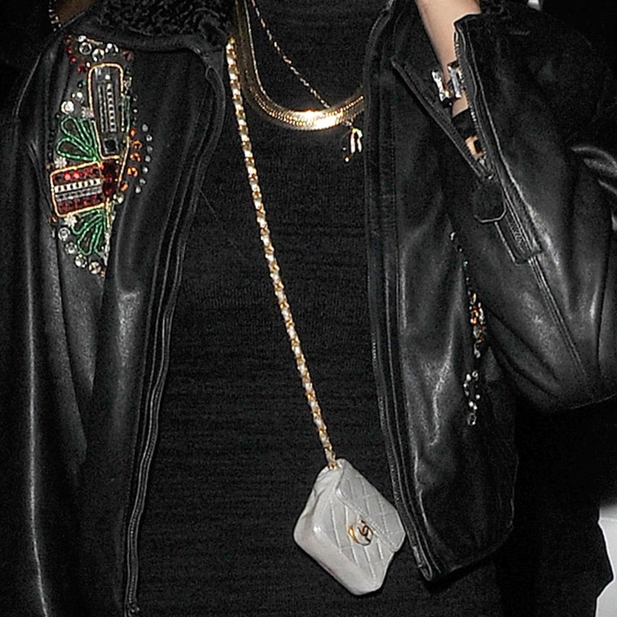 Rihanna accessorizes with Chanel’s tiniest quilted flap bag—an ultra-mini collector’s piece in silver lambskin, worn as a necklace with a gold-tone chain
