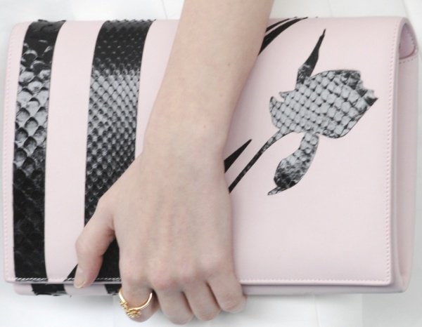 Kendrick carried a structured blush Dior clutch featuring black snakeskin accents and a bold graphic floral motif