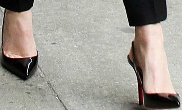 Emma Watson steps out in sleek Christian Louboutin Apostrophy Sling pumps, featuring glossy black patent leather and the designer’s signature red soles