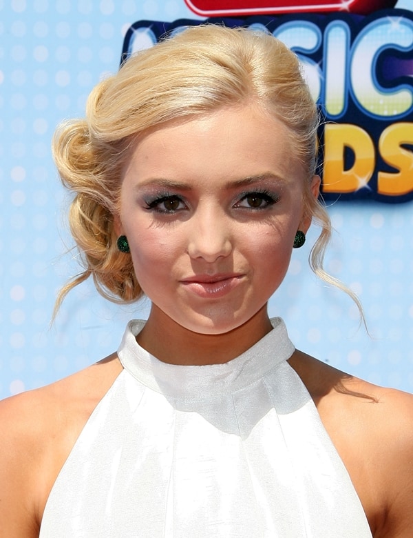 Peyton List's elegant updo and subtle makeup are complemented by her green stud earrings