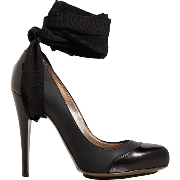The Lanvin cap-toe ankle-strap pumps in black combine a glossy rounded toe with a sculptural stiletto and dramatic grosgrain ankle wrap, originally retailing for $1,150
