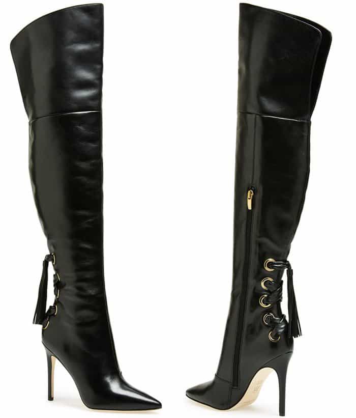 Via Spiga “Femke” over-the-knee boots in black leather feature a sleek pointed toe, slim stiletto heel, and gold-tone grommet lacing with tassel accents at the ankle