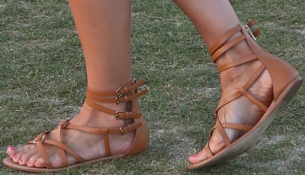 Camilla Belle’s tan gladiator sandals feature multiple ankle straps with gold buckles, adding a chic bohemian touch to her relaxed festival look