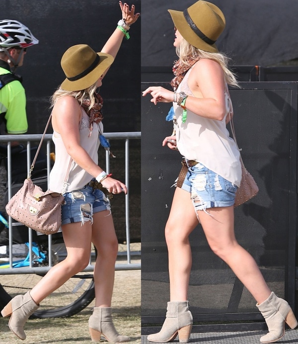 Hilary Duff embraces laid-back Coachella style in a sheer sleeveless top, distressed denim shorts, and gray Rag Bone “Newbury” ankle boots, finished with a wide-brim hat and studded blush Miu Miu bag