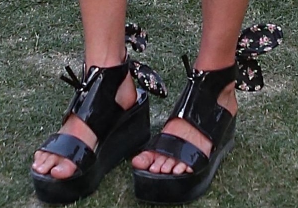 Kate Bosworth adds a playful edge to her Coachella look with chunky black patent flatform sandals tied at the ankles with floral-print bows