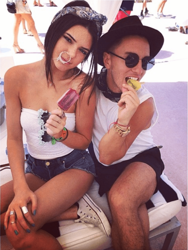 Kendall Jenner cools off at Coachella in denim shorts and a strapless white top, accessorized with a bold oversized nose ring and playful popsicle in hand