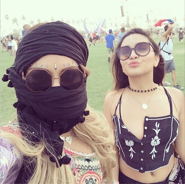 Vanessa Hudgens and her sister Stella Hudgens embrace bohemian desert style at Coachella 2014, protecting themselves from the sandstorm in bold festival looks complete with statement sunglasses, bindis, and layered jewelry