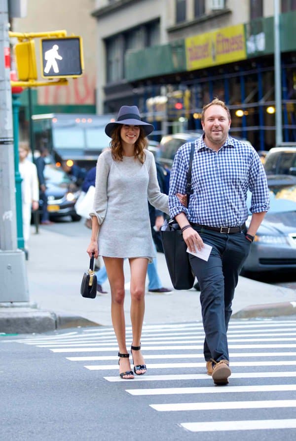Alexa Chung strolling in New York City wearing a chic grey shift dress, paired with a fedora hat and ankle-strap sandals, carrying a Dolce Gabbana bag