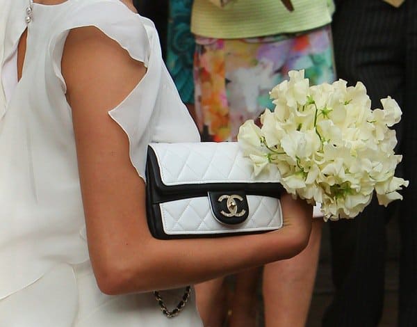 Cara Delevingne carried a two-tone Chanel flap bag in classic black and white quilting, adding a chic designer touch to her bridesmaid look