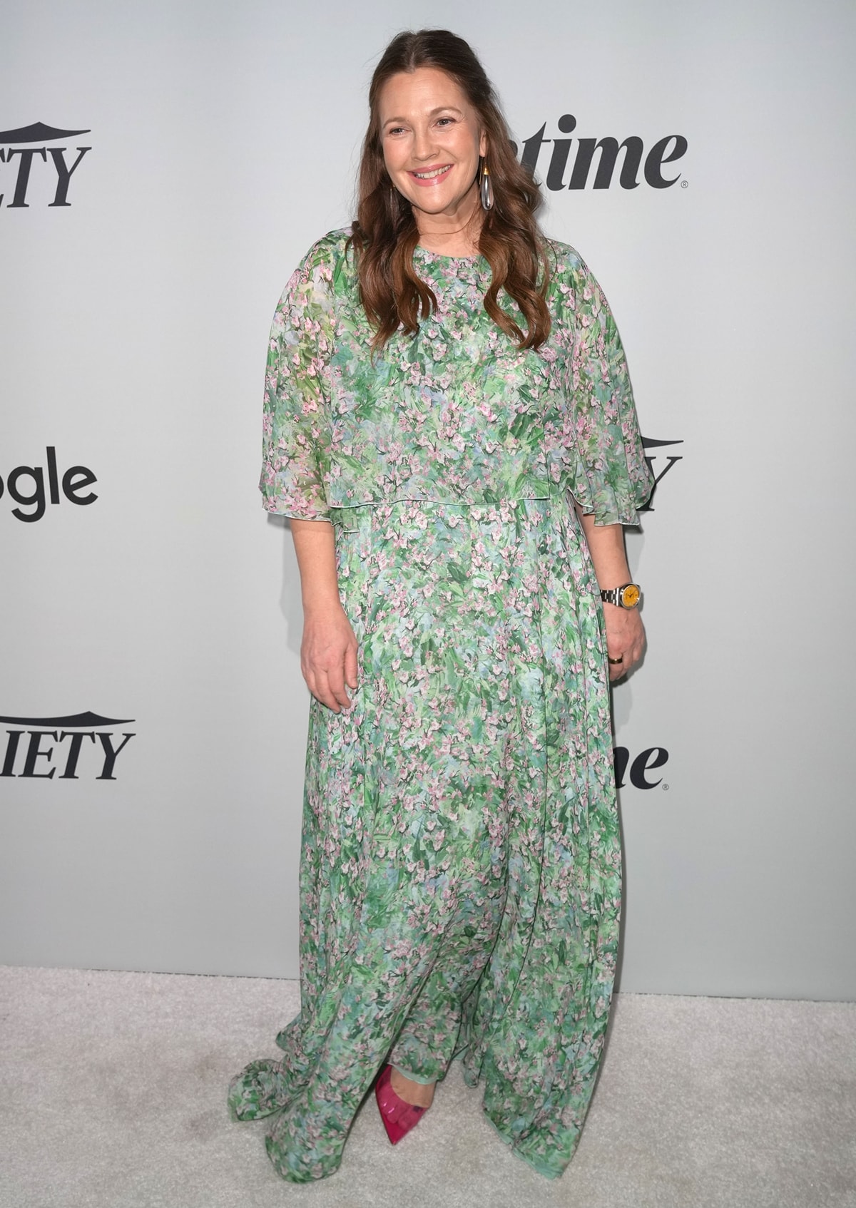 Drew Barrymore pairs her flowing, floral silk Giambattista Valli dress with vibrant pink, pointed-toe pumps, adding a bold pop of color beneath the soft, romantic silhouette at Variety’s 2022 Power of Women event in New York City