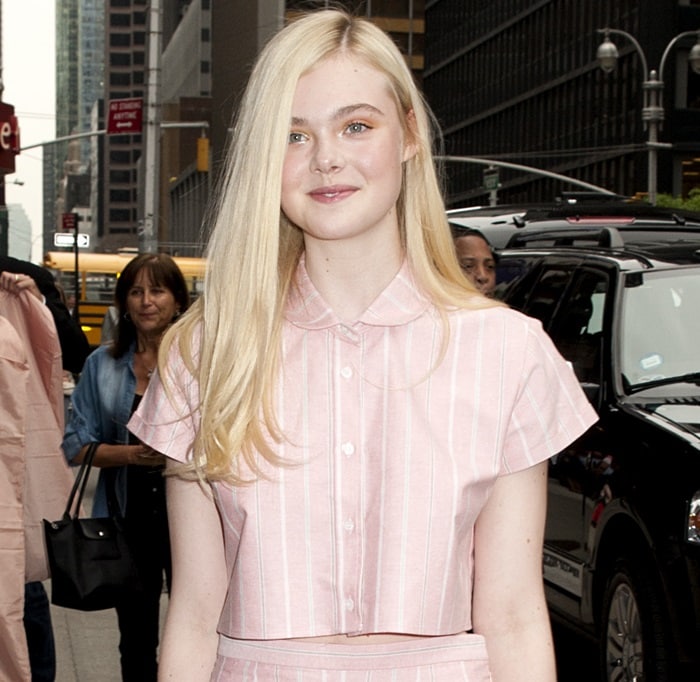 Elle Fanning channels effortless charm in a pink striped crop top and matching pants, bringing pajama chic to the streets of New York City