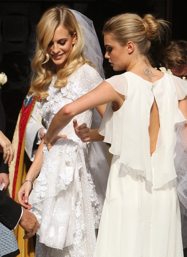 Cara Delevingne revealed her upper back Yantra-inspired tattoo while adjusting Poppy Delevingne’s custom Chanel wedding dress