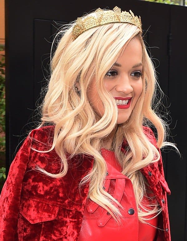 Rita Ora in a close-up shot, highlighting her golden crown and radiant smile while promoting her new single