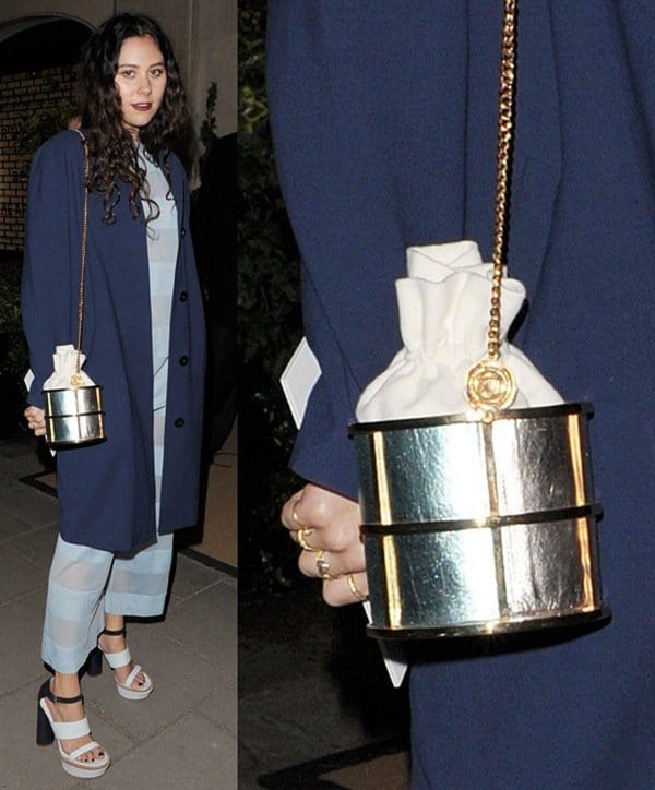 Eliza Doolittle embraces playful fashion with a metallic lunch box-inspired handbag, pairing it with striped separates, a navy overcoat, and bold platform heels at the Mulberry dinner during London Fashion Week