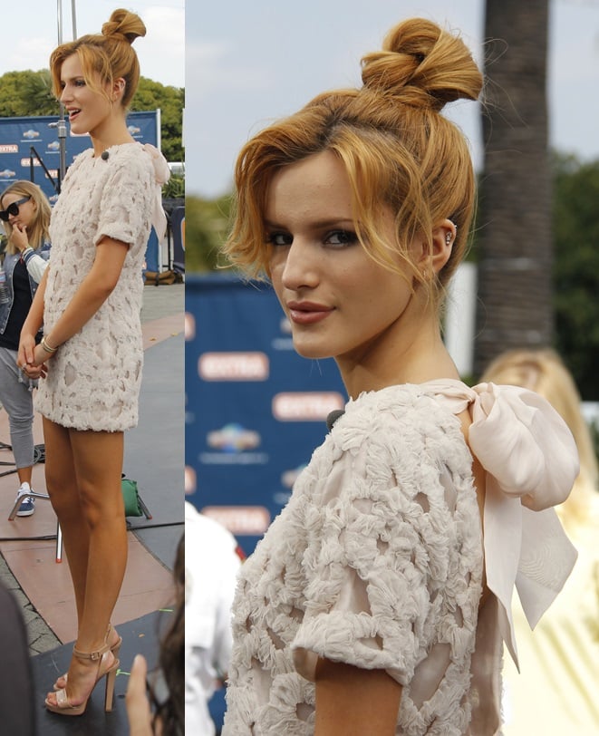 Her airy mini-dress featured romantic floral appliqués and an oversized bow accent, perfectly paired with a soft top-knot and natural makeup for a sweet-meets-modern finish