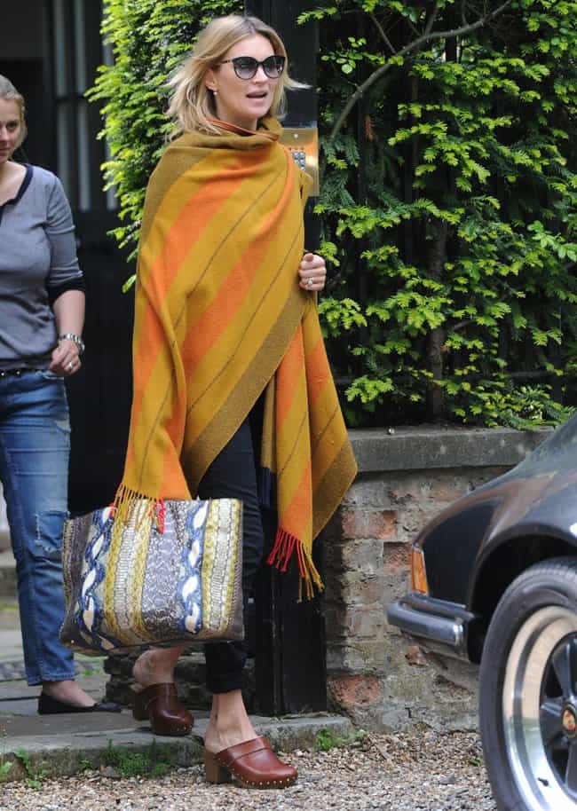 Kate Moss effortlessly styles wooden platform clogs with cuffed jeans and a bold striped wrap, proving clogs can look chic with the right accessories