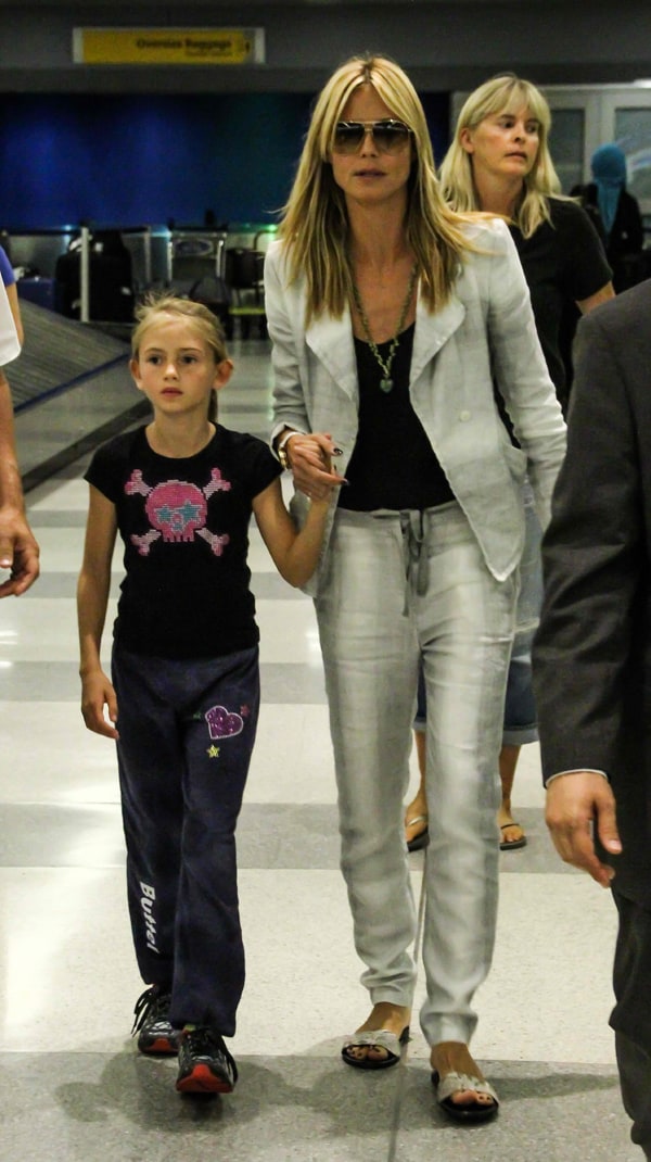 Heidi Klum keeps her airport look effortlessly chic in a light gray blazer and matching drawstring pants, paired with flat sandals and oversized sunglasses