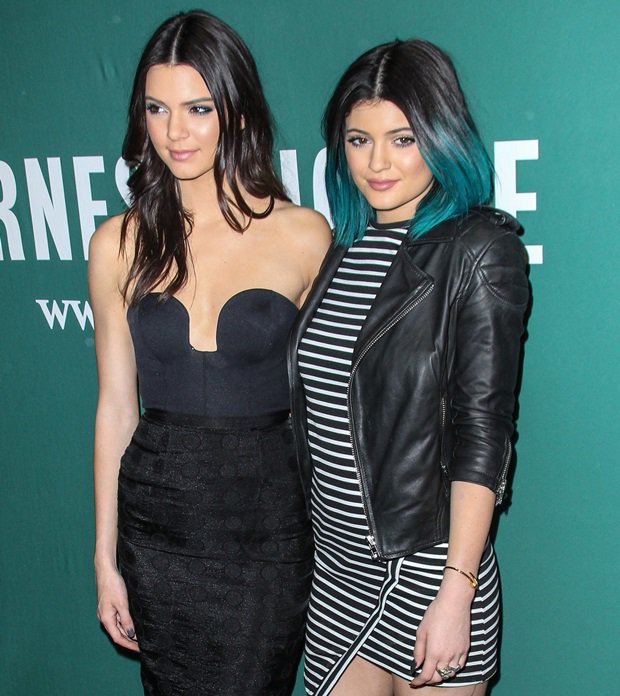 Kendall Jenner opts for sleek sophistication in a strapless black bustier dress, while Kylie Jenner contrasts with a striped mini dress and edgy leather jacket at Barnes Noble on Union Square in New York City