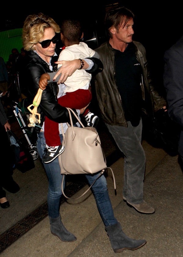 Charlize Theron keeps it airport-chic in skinny jeans and suede ankle boots, accessorized with a beige Louis Vuitton Soft Lockit tote while traveling with Sean Penn and son Jackson