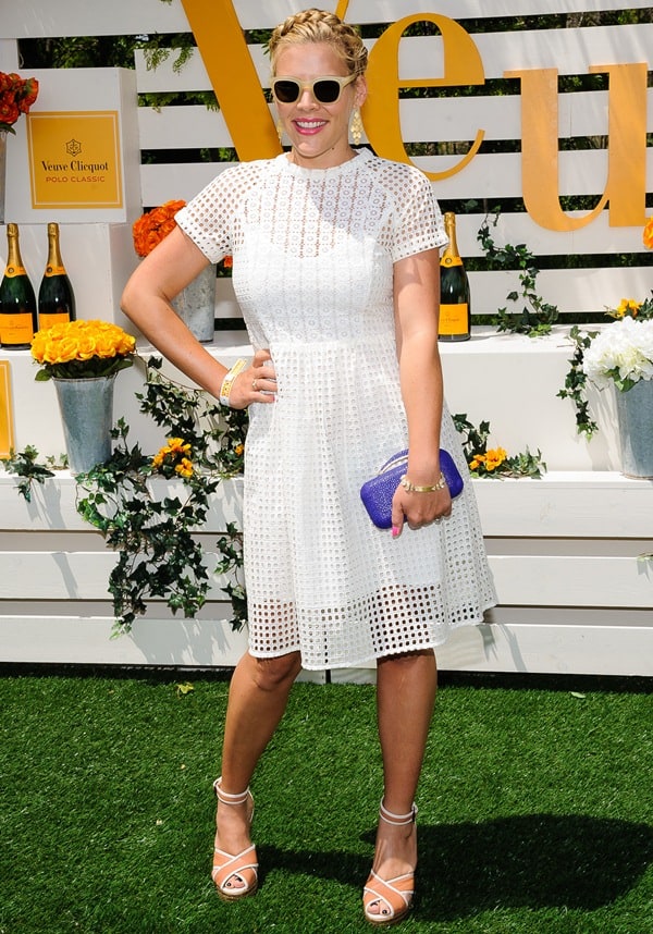 Busy Philipps keeps it playful in a breezy white eyelet dress, paired with strappy Lanvin wedges, retro sunglasses, and a bold purple clutch