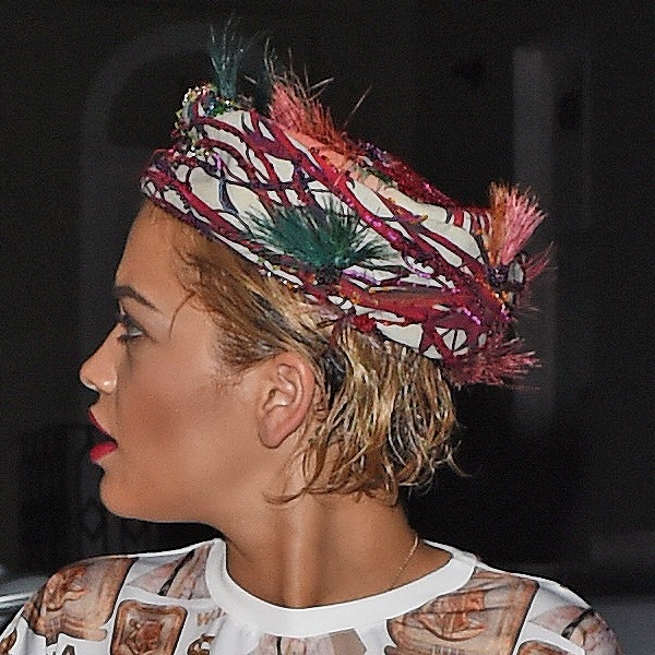Rita Ora completes her look with a feathered headscarf resembling a bird's nest