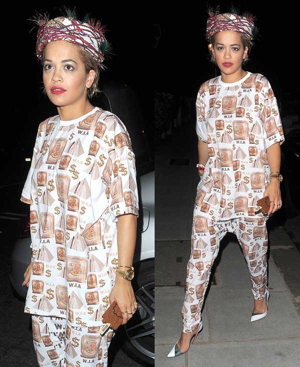 Rita Ora wearing a baggy W.I.A. Collections outfit that features an Egyptian-themed print made up of pyramids, hieroglyphs, and dollar signs