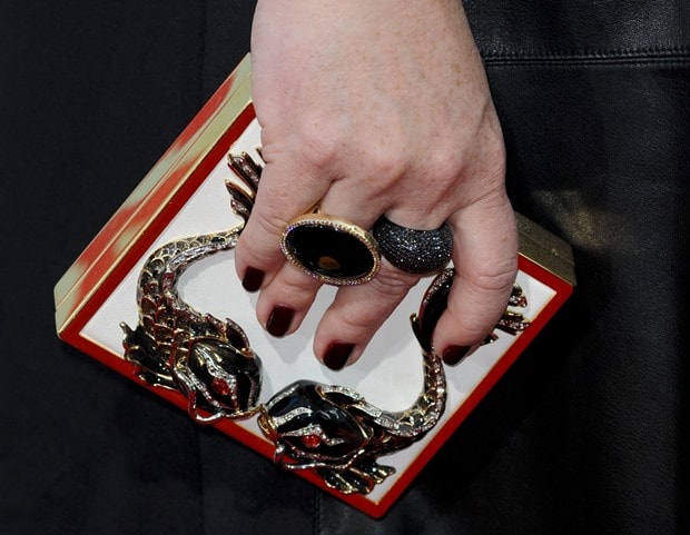 Melissa McCarthy showing off a boxy embellished clutch and stacks of rings