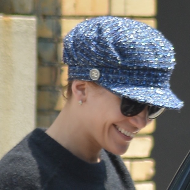 J.Lo flashes a smile while sporting a chic, blue newsboy cap from Chanel, adding a touch of sparkle to her outfit