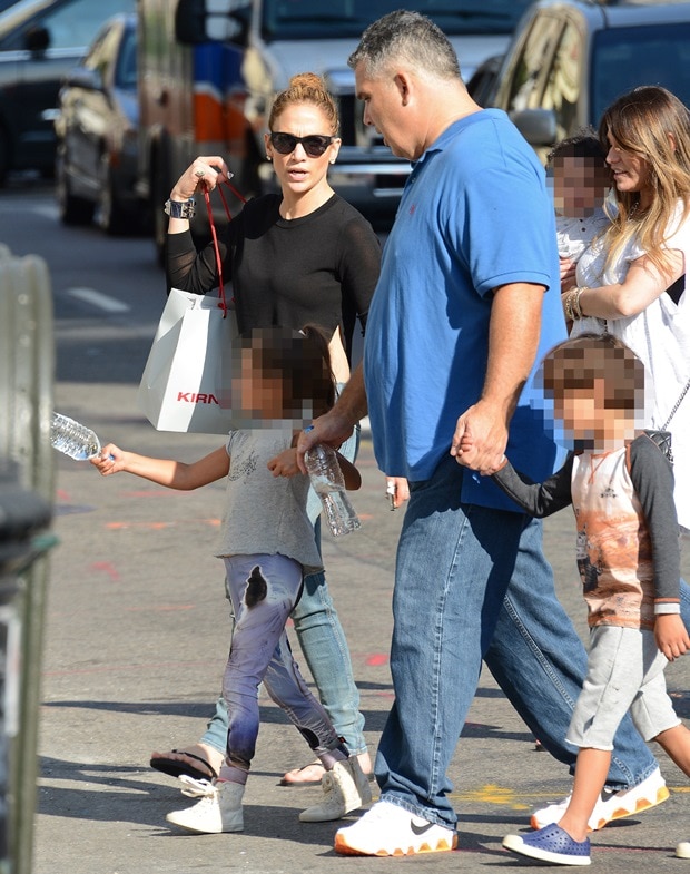 Jennifer Lopez keeps it casual while shopping in Soho, wearing distressed jeans, a black long-sleeve top, and chic sunglasses, accessorized with a Hermès bracelet and flip-flops