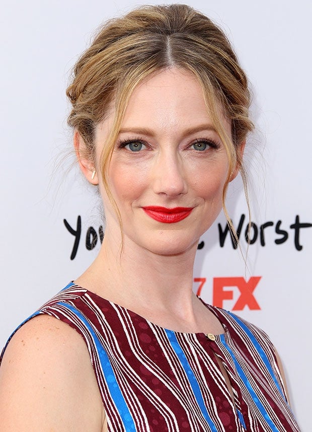 Judy Greer wears a striped sleeveless dress with a keyhole neckline and red lipstick