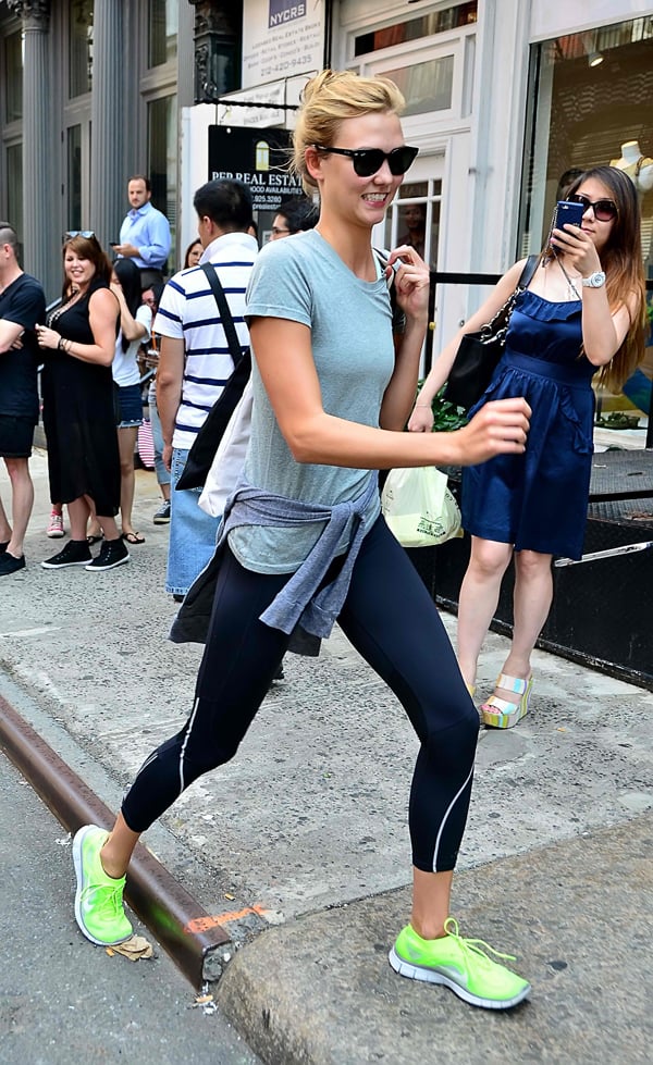 Karlie Kloss in casual wear with sweatpants, a shirt, and neon sneakers