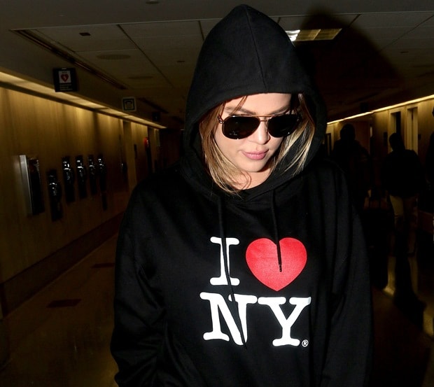 Khloé Kardashian keeps her look minimal yet chic, with natural makeup and straight, blonde-highlighted hair peeking out from under her hoodie