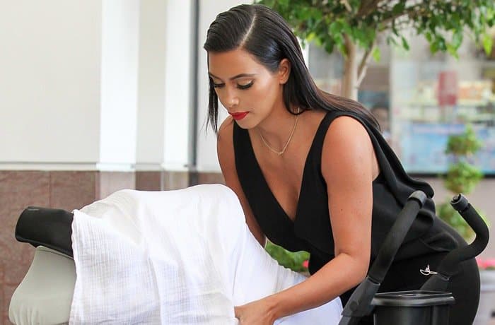 Kim Kardashian effortlessly embraces minimalism in a sleek V-neck black jumpsuit, showcasing her chic and elegant style