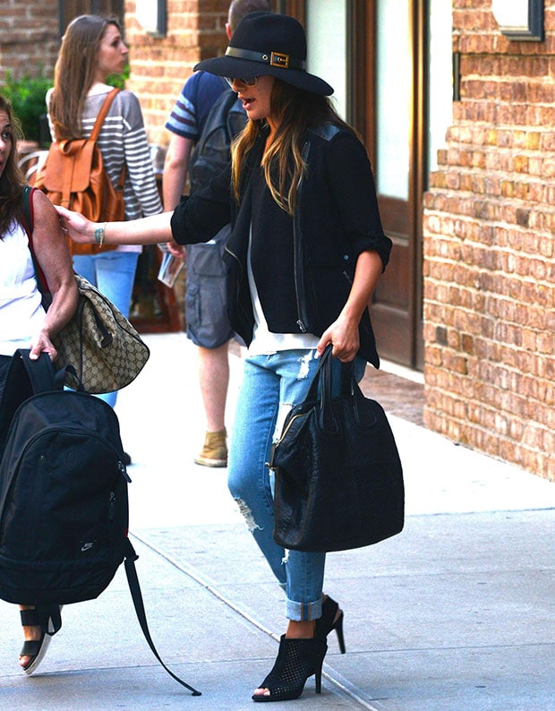Lea Michele masters effortless street-chic style in a black fedora, asymmetrical zip jacket, distressed boyfriend jeans, and perforated peep-toe booties