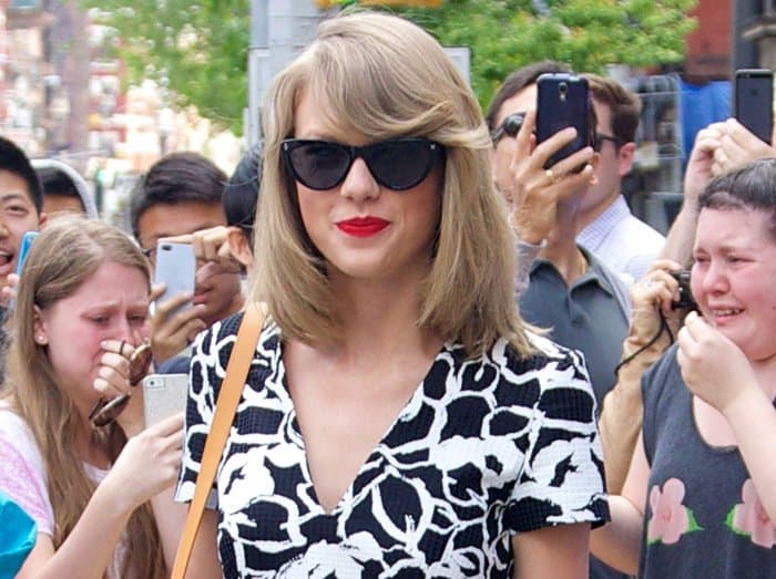 Taylor Swift stuns in a black and white patterned romper complete with bold red lipstick and chic sunglasses