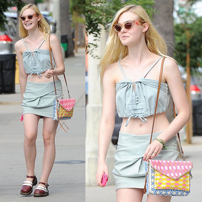Elle Fanning shows off her midriff in a playful denim crop top and skirt, accessorized with a colorful Rebecca Minkoff bag and Dr. Martens x Agyness Deyn shoes