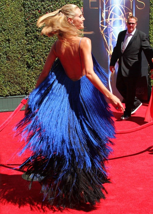 A mid-spin moment showcases the gown’s fluid architecture from the back, with the low-cut silhouette and sweeping fringe emphasizing movement against the structured lift of her heels
