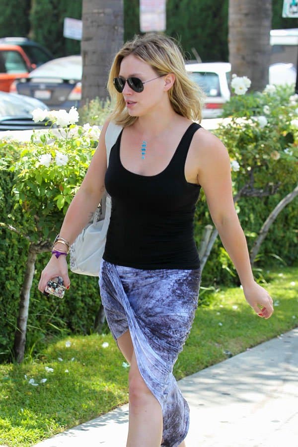 Hilary Duff wearing a black tank top and a printed asymmetrical wrap skirt with aviator sunglasses