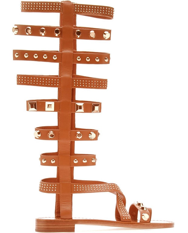 Signature 18-karat gold-plated hardware and Italian vachetta harness straps add gladiator-inspired drama to a tall, knee-high boot styled with a modern crisscrossed vamp and ultra-chic toe ring