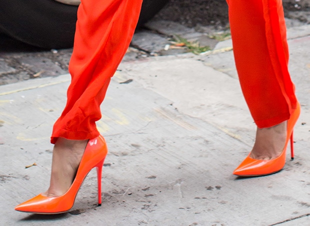 These vibrant orange point-toe pumps feature a high-gloss finish and a slim stiletto heel, perfectly matching the ensemble's monochromatic theme