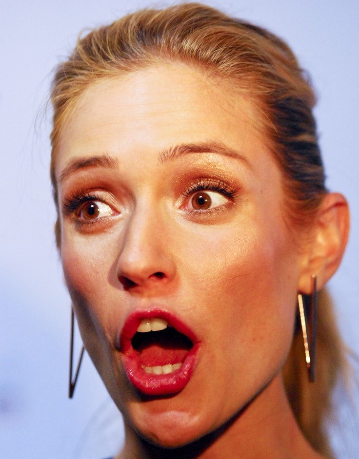 Kristin Cavallari shows off her bold red lip and sleek gold bar earrings while striking an animated expression on the red carpet