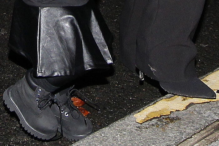 A close-up reveals North West’s sturdy toddler Timberland boots next to Kim Kardashian’s sharp black pointed-toe heels as they head into the Balenciaga presentation