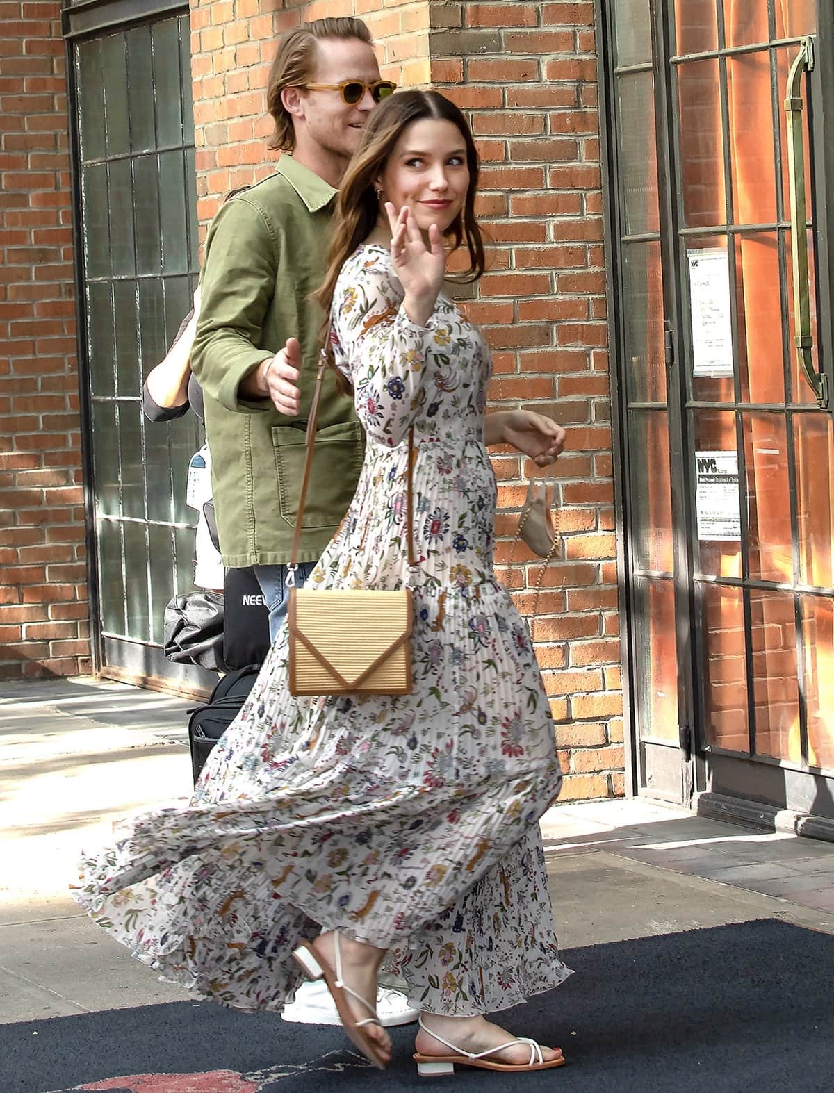 Sophia Bush pairs a flowing floral maxi dress with minimalist white strappy sandals and a woven geometric crossbody bag while stepping out in New York City