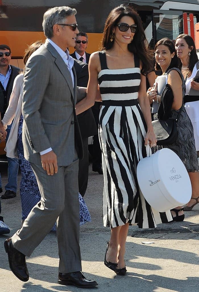 Amal Alamuddin stuns in a striped Dolce Gabbana dress and black pumps, while George Clooney looks dapper in a grey suit as they arrive in Venice