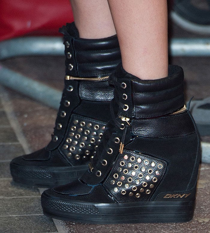 Cara Delevingne’s DKNY “Griffin” wedge sneakers feature quilted leather, gold-tone grommet detailing, side zippers, and hidden wedge heels for a bold, street-style edge
