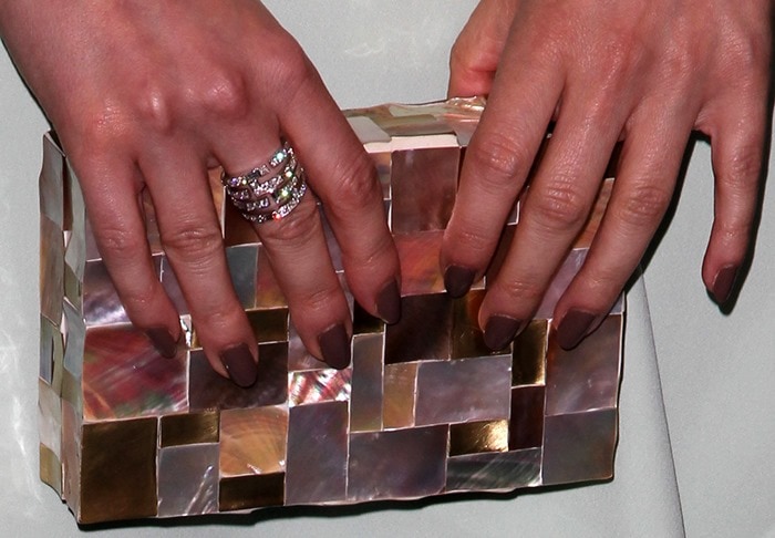 A close-up of Lizzy Caplan’s geometric Emm Kuo minaudière reveals its glossy mother-of-pearl mosaic finish and her chic mauve manicure