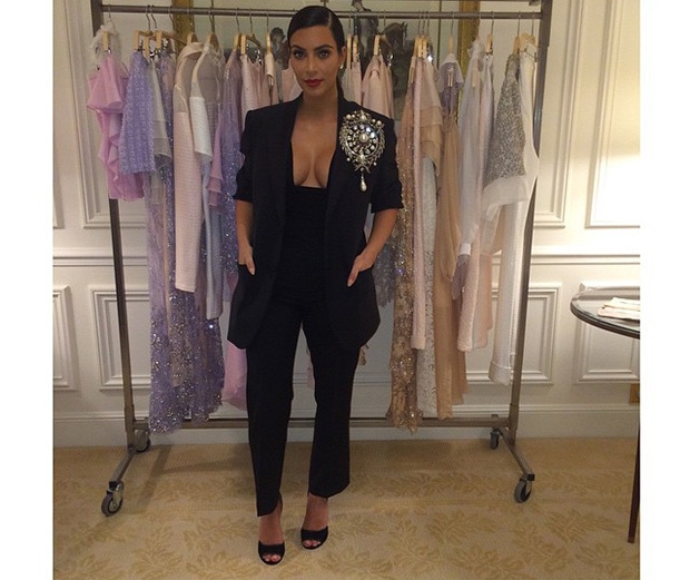 Kim Kardashian attended Carine Roitfeld's CR Fashion Book party in Paris wearing a chic Givenchy ensemble with a low-cut top, tuxedo blazer featuring an oversized brooch, and classic black open-toe heels