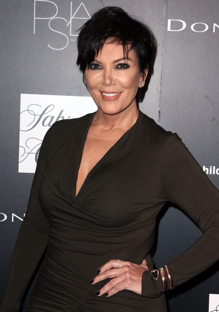 Kris Jenner showcases her signature glam with a sleek jet-black pixie haircut, smoky eye makeup, and a soft nude lip