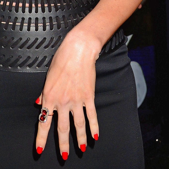 Megan Fox's bold Rouge Louboutin red manicure perfectly complements her statement ruby ring, adding a striking pop of color against her sleek black ensemble