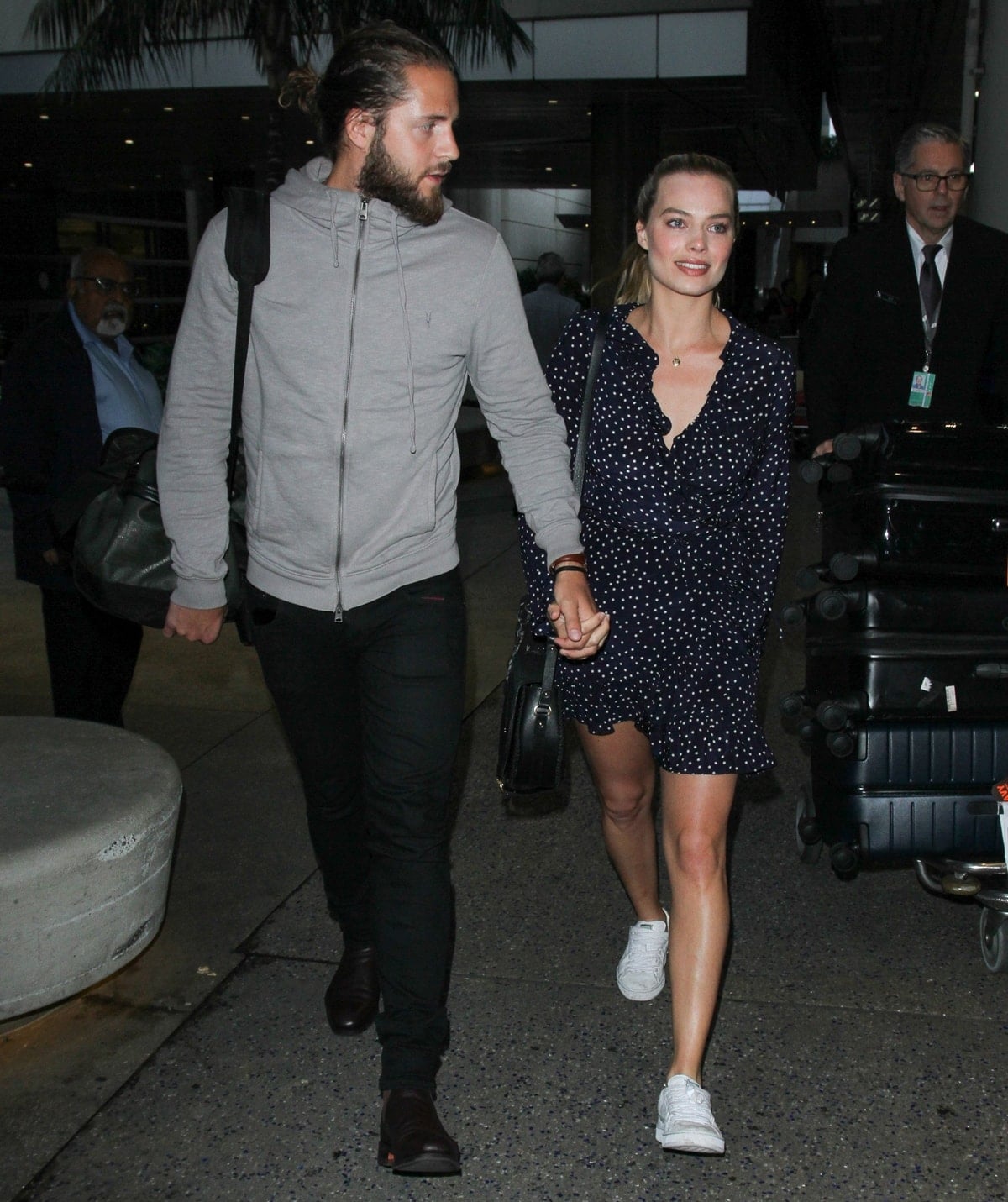 Margot Robbie steps out in a casual navy polka dot dress paired with white sneakers, holding hands with husband Tom Ackerley